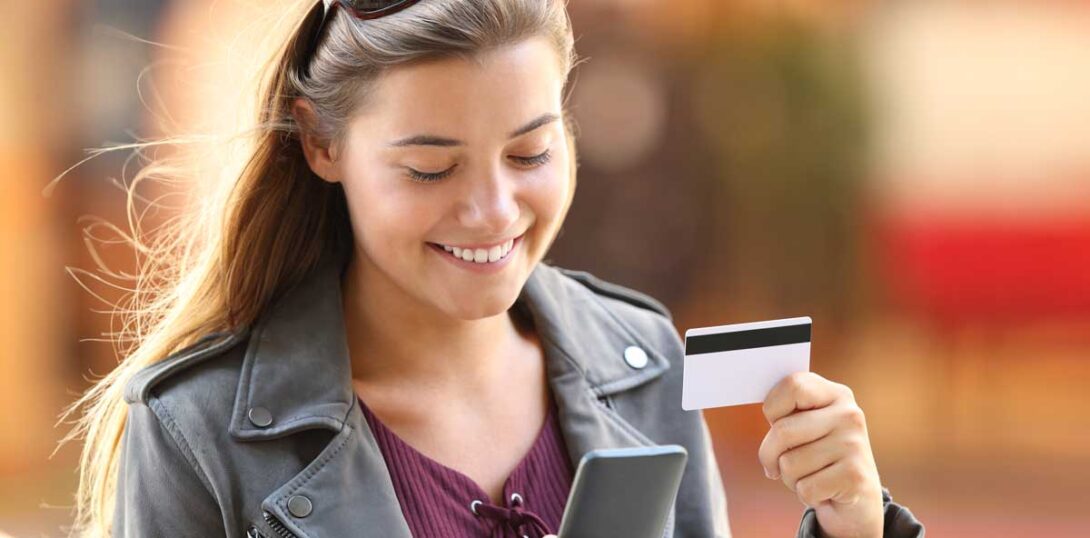 Teenage girl shopping on smartphone with credit card