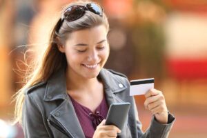 Teenage girl shopping on smartphone with credit card